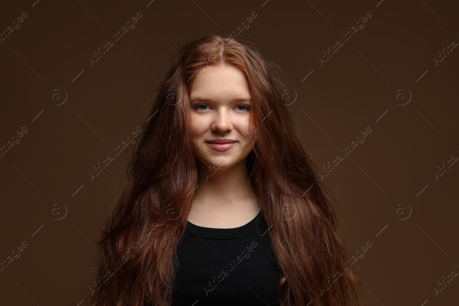 Portrait of beautiful teenage girl with healthy wavy hair on brown background Photo of Portrait of beautiful teenage girl with healthy wavy hair on brown background