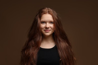 Photo of Portrait of beautiful teenage girl with healthy wavy hair on brown background