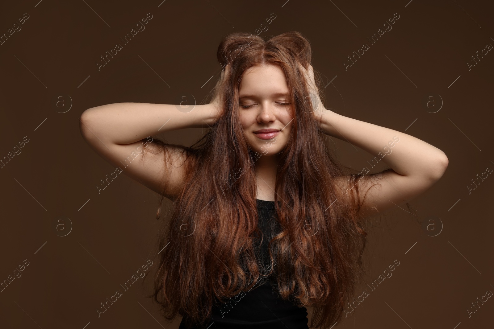 Beautiful teenage girl with healthy wavy hair on brown background Photo of Beautiful teenage girl with healthy wavy hair on brown background