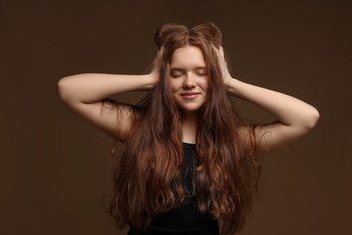 Photo of Beautiful teenage girl with healthy wavy hair on brown background