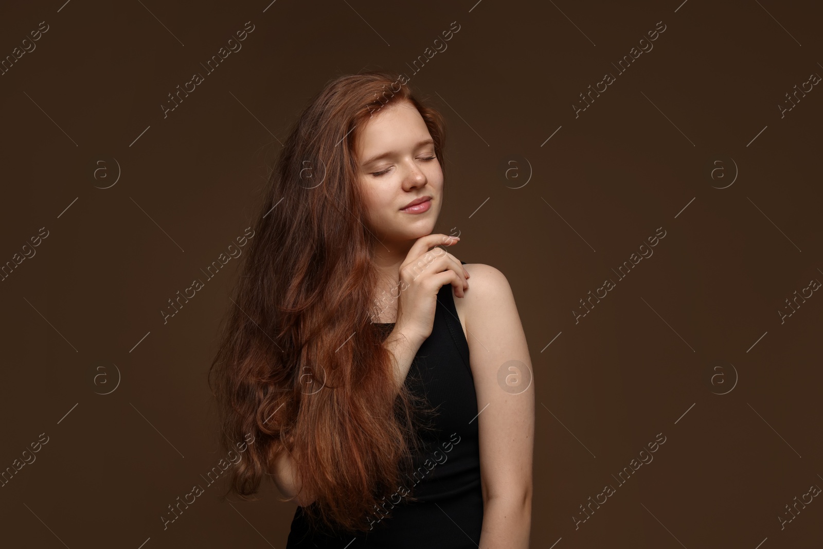 Beautiful teenage girl with healthy wavy hair on brown background Photo of Beautiful teenage girl with healthy wavy hair on brown background