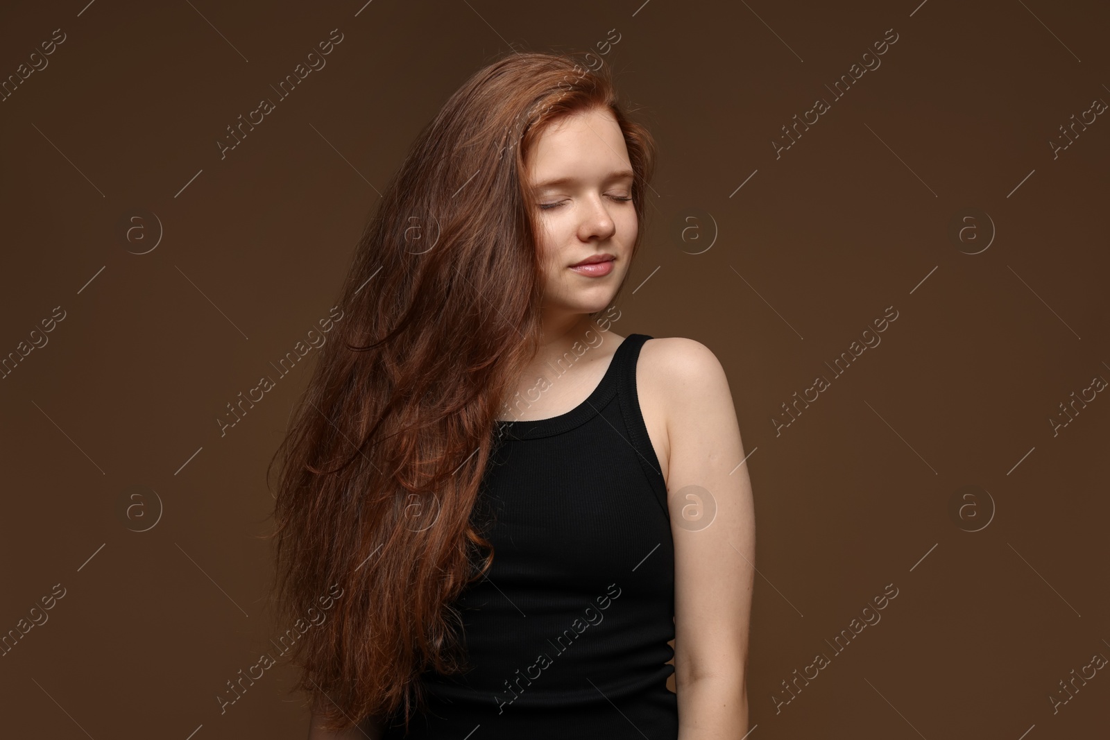 Photo of Beautiful teenage girl with healthy wavy hair on brown background
