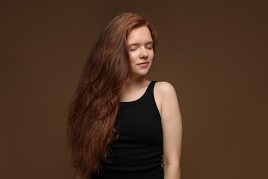 Photo of Beautiful teenage girl with healthy wavy hair on brown background