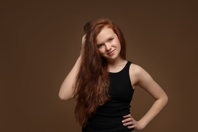 Photo of Portrait of beautiful teenage girl with healthy wavy hair on brown background