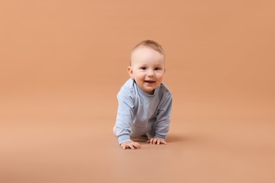 Photo of Cute little baby crawling on beige background