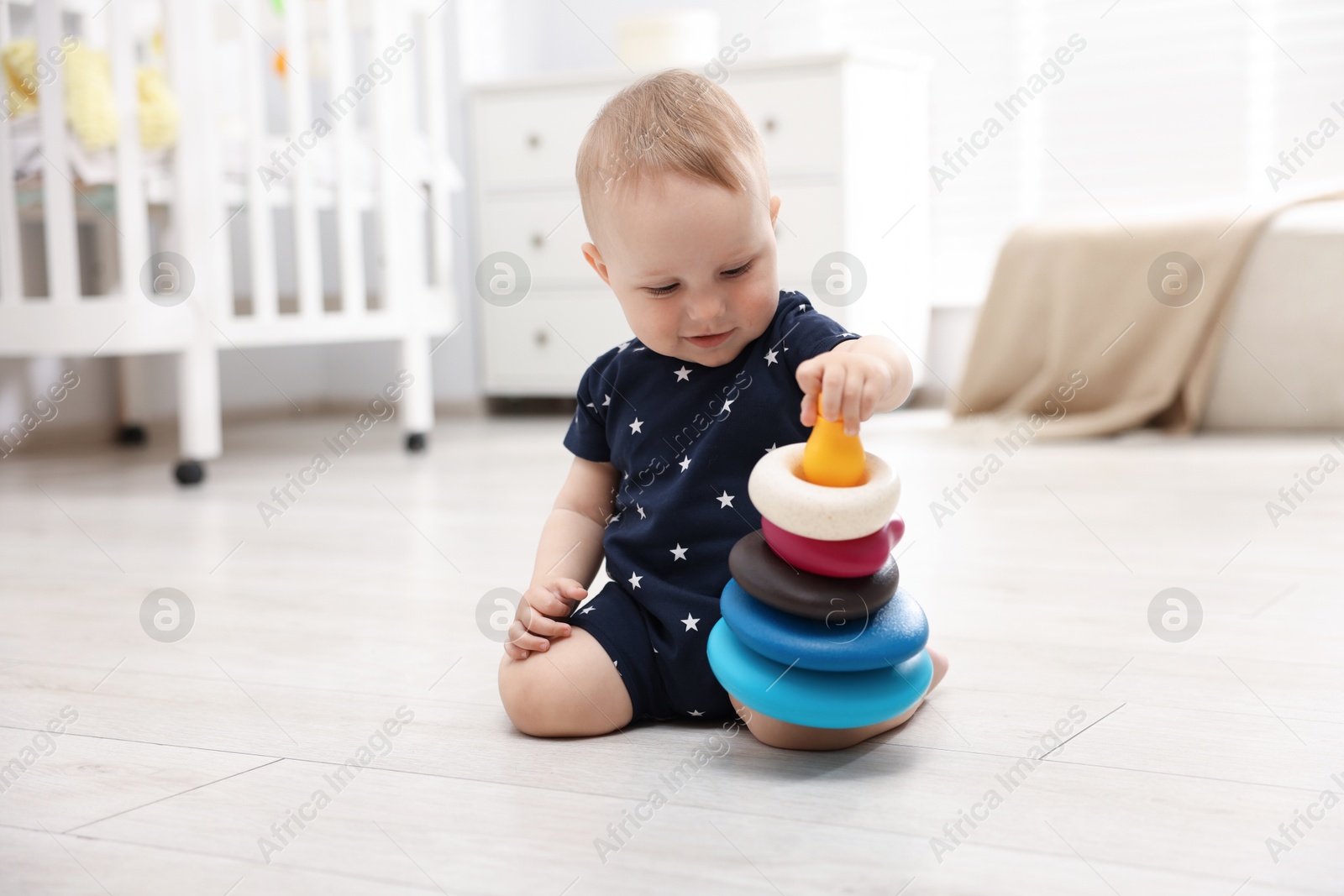 Cute little baby playing with toy pyramid in room Photo of Cute little baby playing with toy pyramid in room