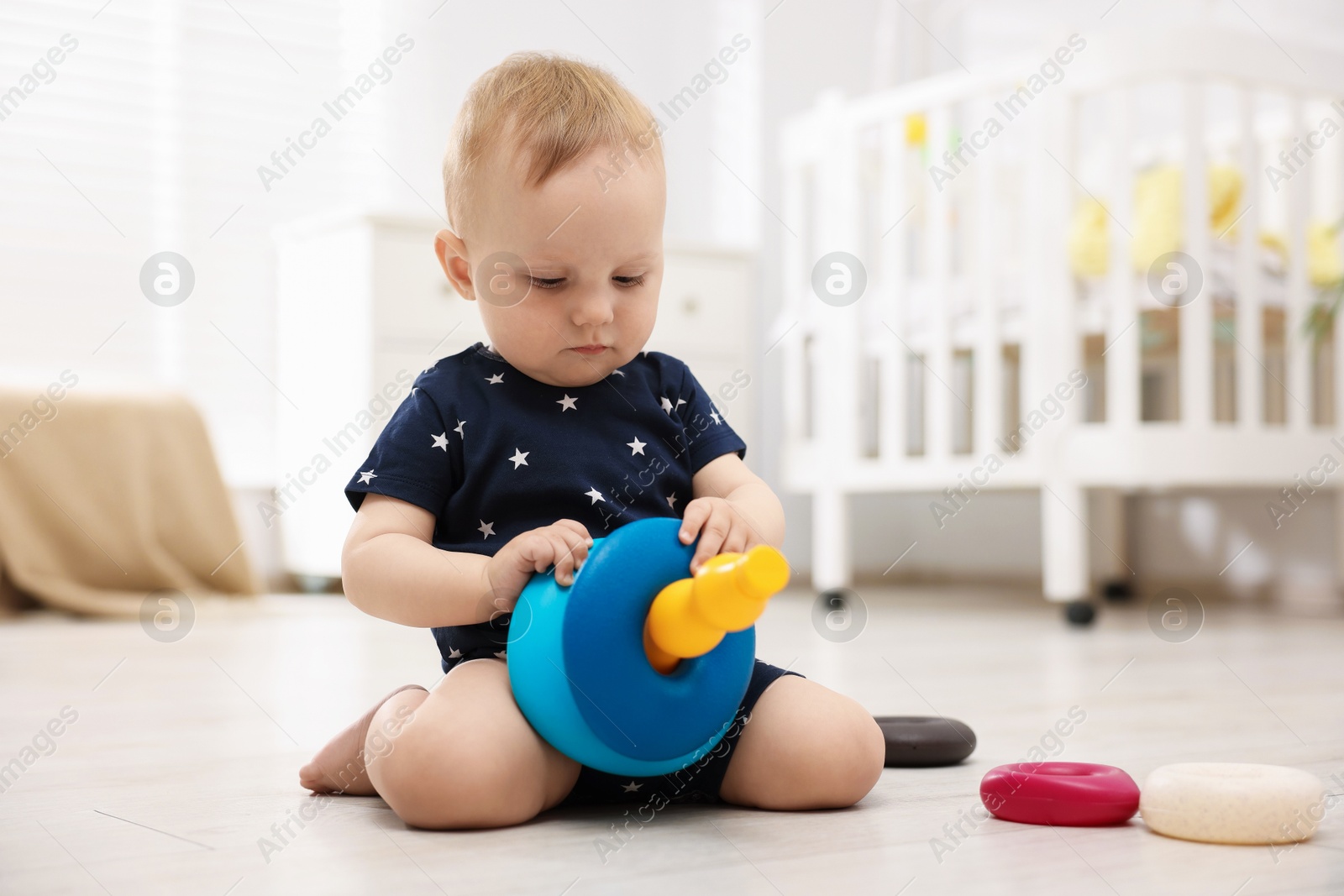 Cute little baby playing with toy pyramid in room Photo of Cute little baby playing with toy pyramid in room