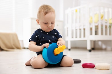 Photo of Cute little baby playing with toy pyramid in room