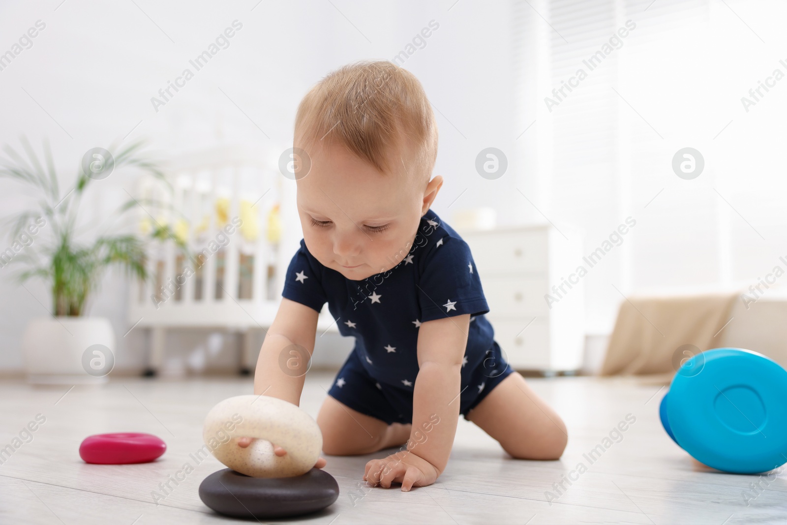 Cute little baby playing with toy pyramid in room Photo of Cute little baby playing with toy pyramid in room