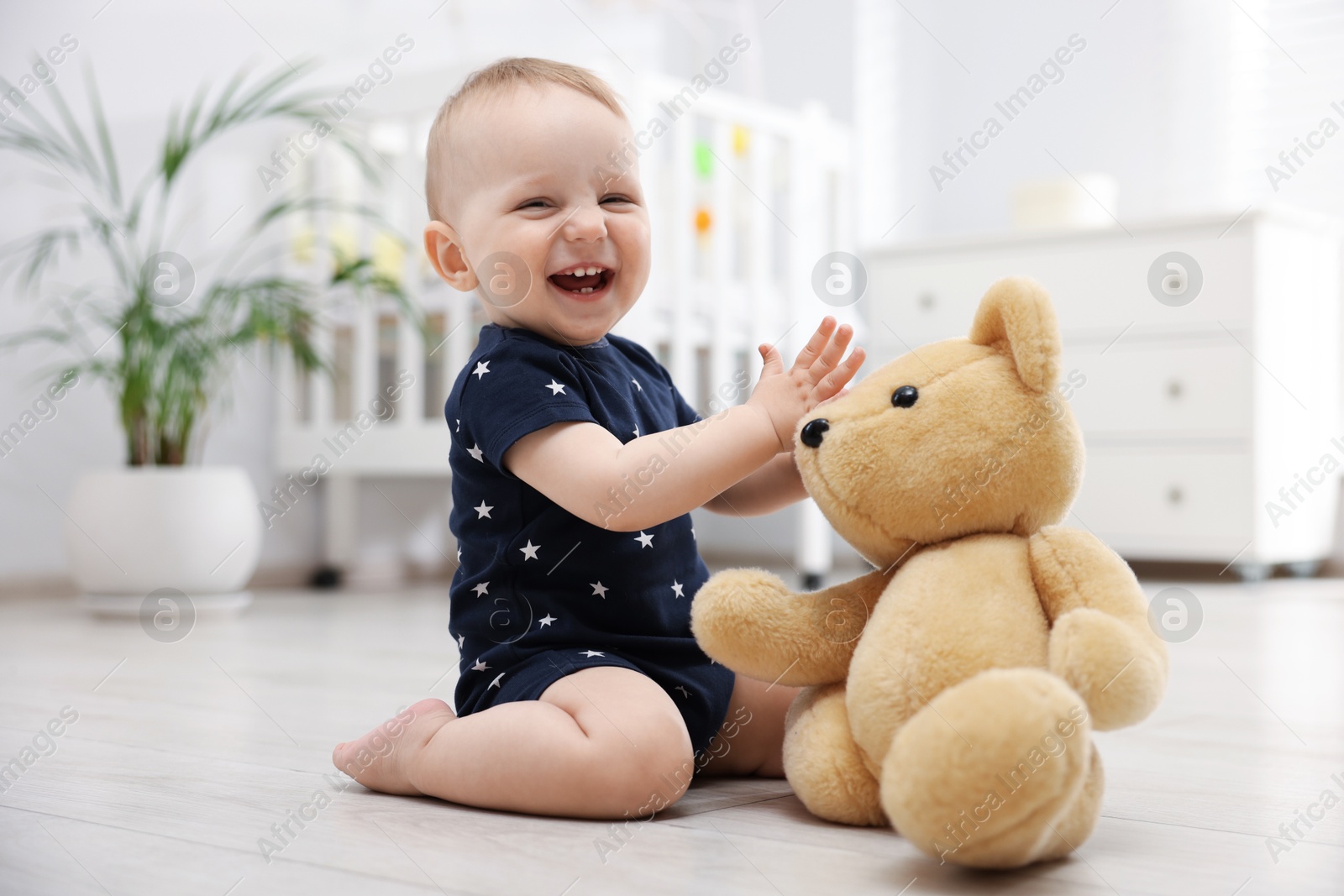 Cute little baby playing with teddy bear in room Photo of Cute little baby playing with teddy bear in room