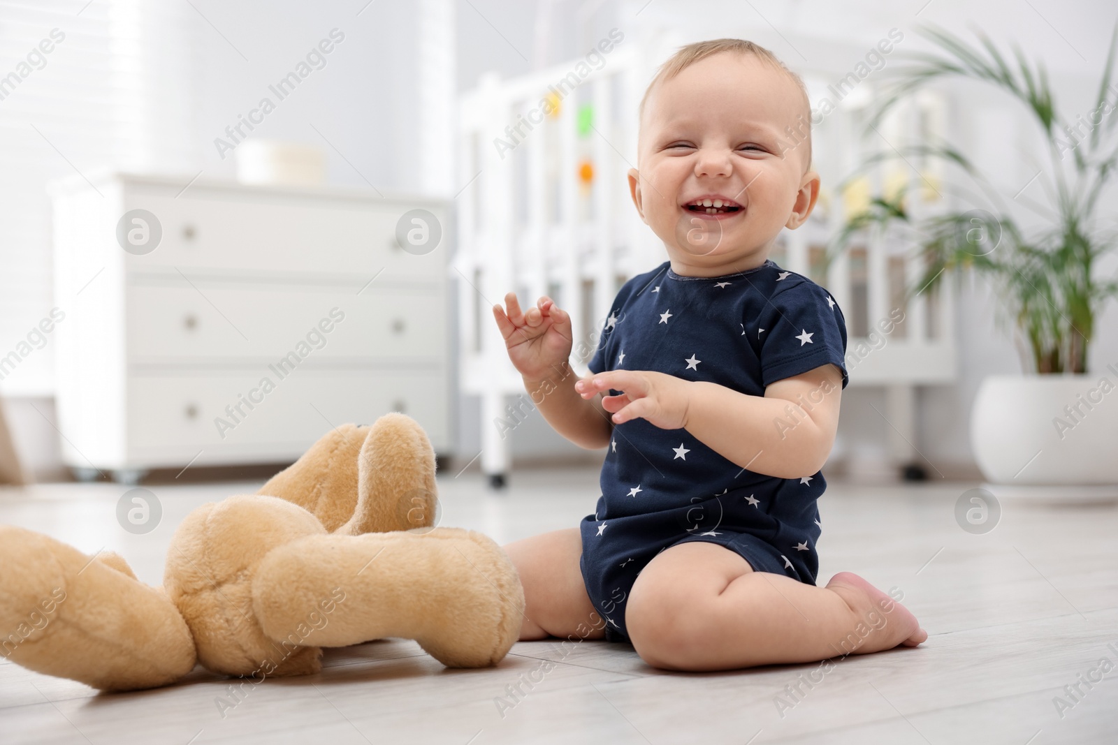 Cute little baby playing with teddy bear in room Photo of Cute little baby playing with teddy bear in room