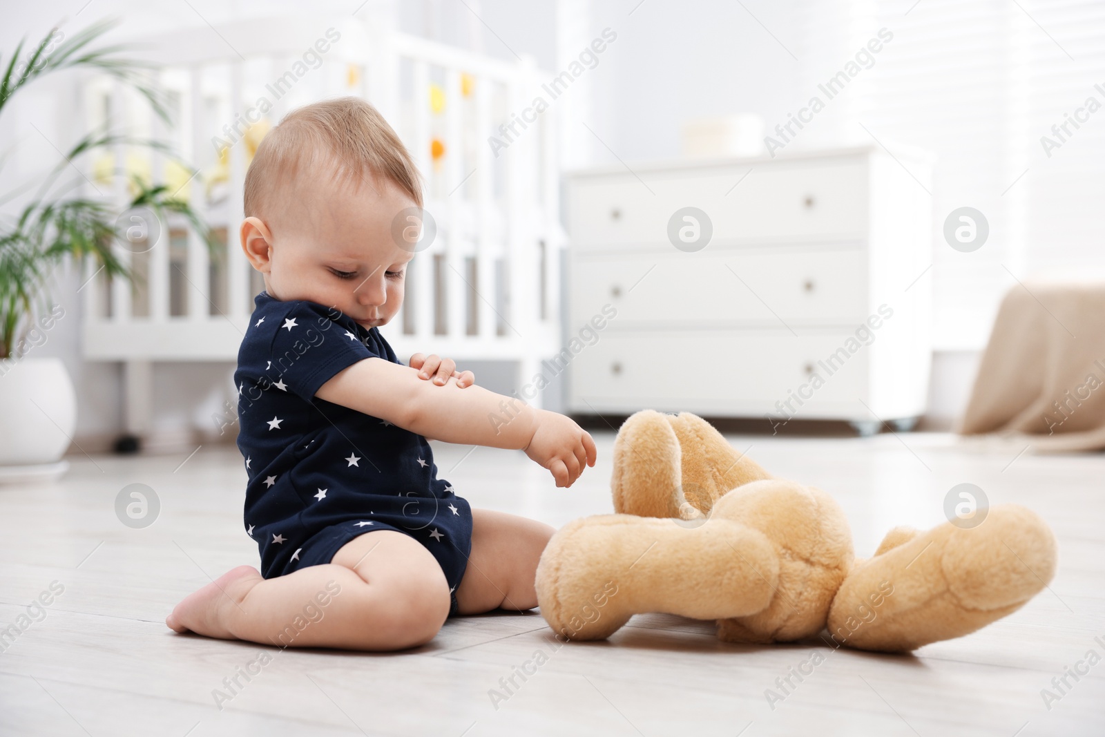 Cute little baby playing with teddy bear in room Photo of Cute little baby playing with teddy bear in room