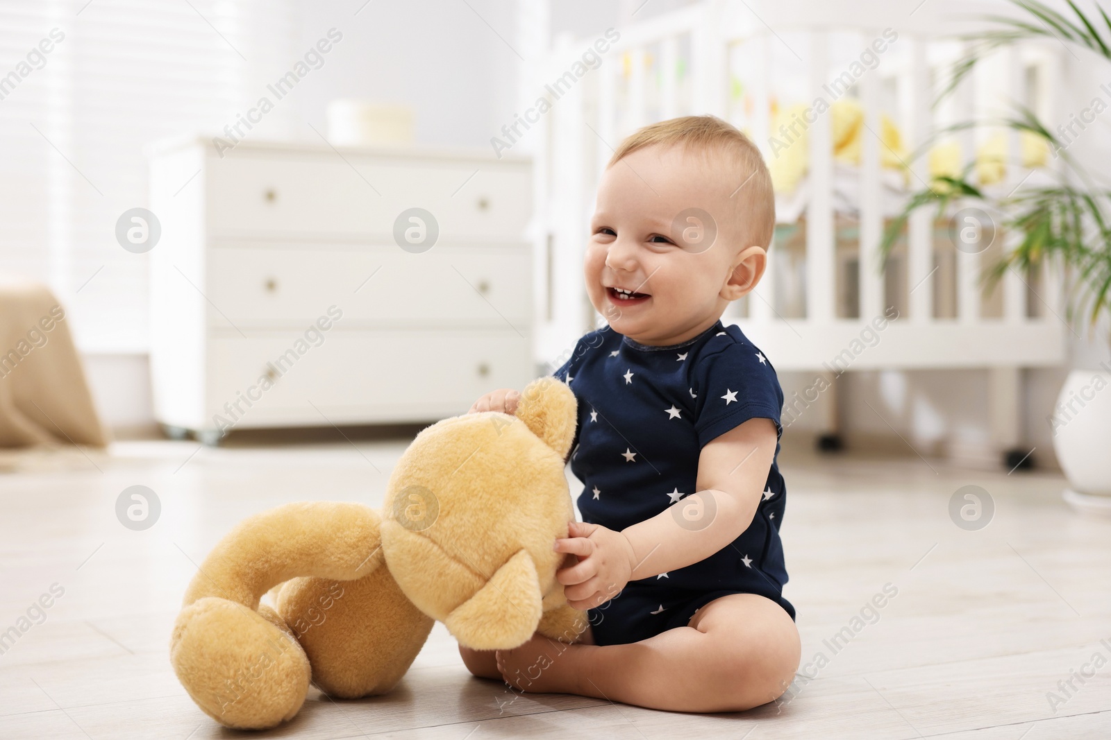 Cute little baby playing with teddy bear in room Photo of Cute little baby playing with teddy bear in room