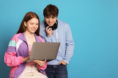 Photo of Teenage girl and boy with laptop on light blue background. Space for text