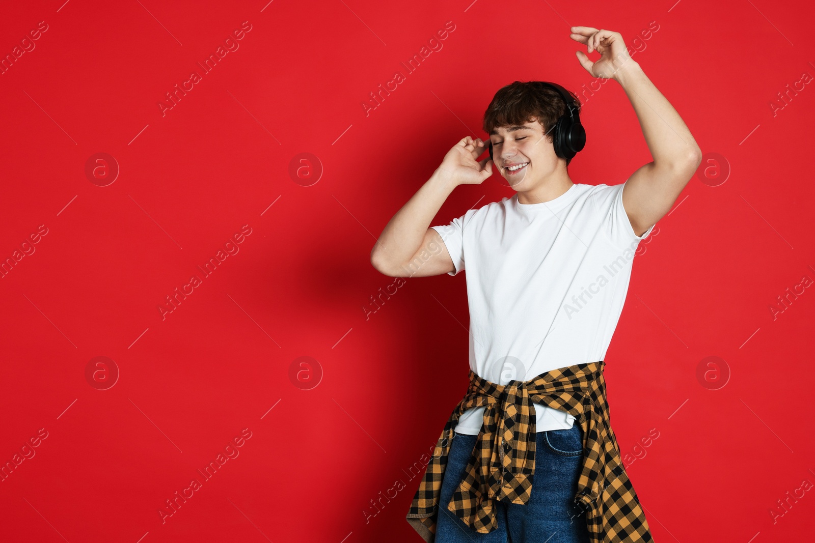 Teenage boy listening to music on red background. Space for text Photo of Teenage boy listening to music on red background. Space for text