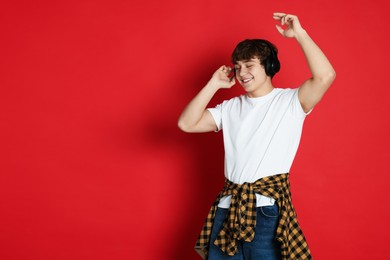 Photo of Teenage boy listening to music on red background. Space for text