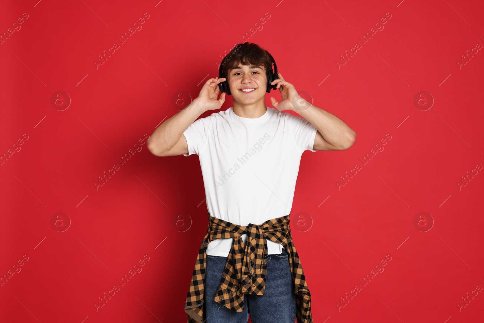 Teenage boy listening to music on red background Photo of Teenage boy listening to music on red background