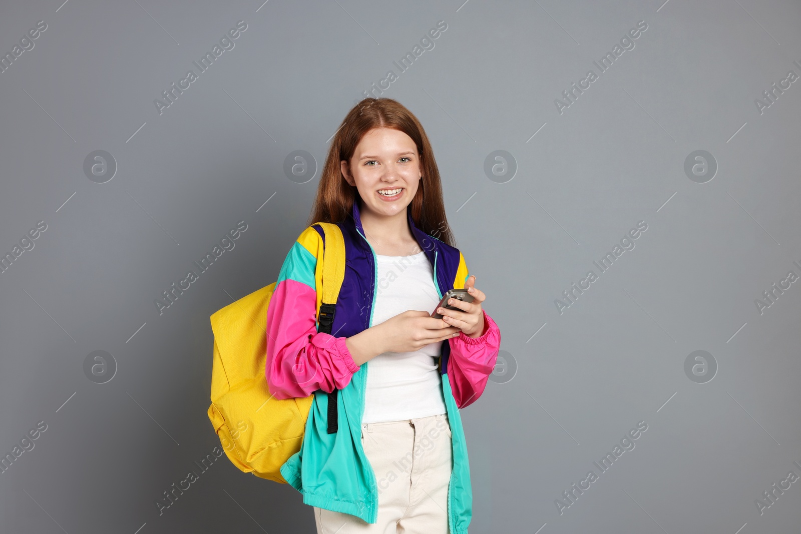 Teenage girl with smartphone on grey background. Space for text Photo of Teenage girl with smartphone on grey background. Space for text