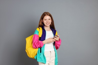 Photo of Teenage girl with smartphone on grey background. Space for text