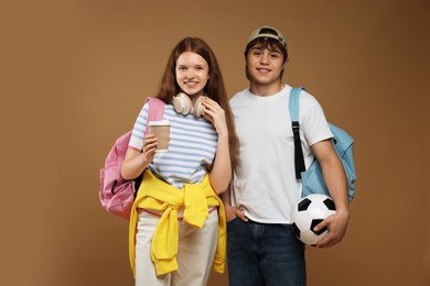 Photo of Teenagers with backpacks, soccer ball and drink on brown background