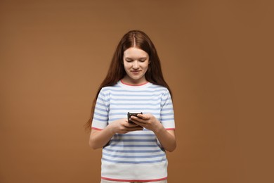 Photo of Teenage girl with smartphone on brown background