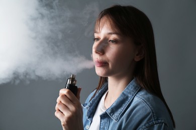 Photo of Woman using electronic smoking device on grey background
