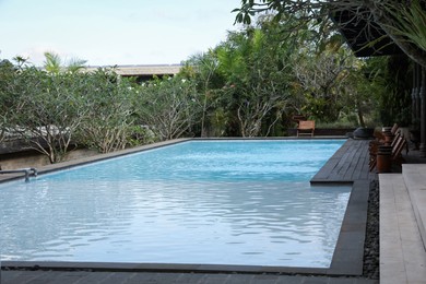 Photo of Outdoor swimming pool, sunbeds and green plants at luxury resort