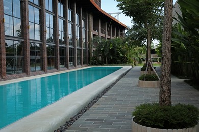 Photo of Outdoor swimming pool and green plants near building at luxury resort