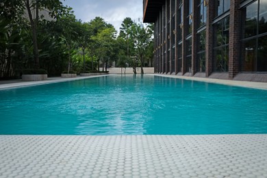 Photo of Outdoor swimming pool and green plants near building at luxury resort, closeup