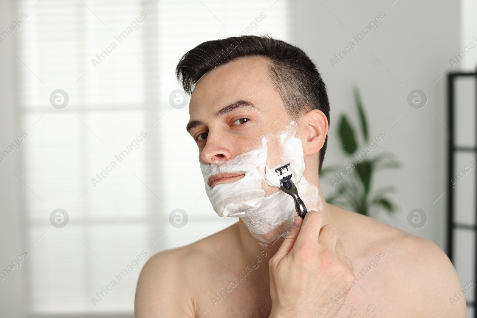Handsome man shaving with razor at home Photo of Handsome man shaving with razor at home