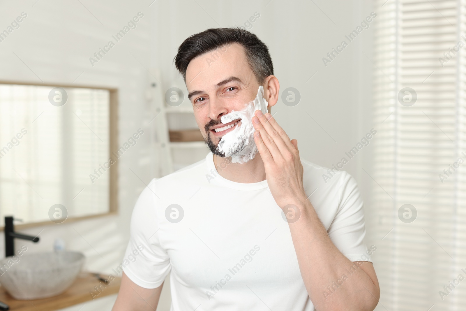 Smiling man applying shaving foam in bathroom Photo of Smiling man applying shaving foam in bathroom