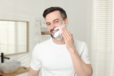 Photo of Smiling man applying shaving foam in bathroom