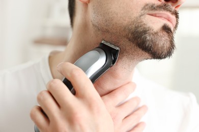 Photo of Man shaving with trimmer at home, closeup