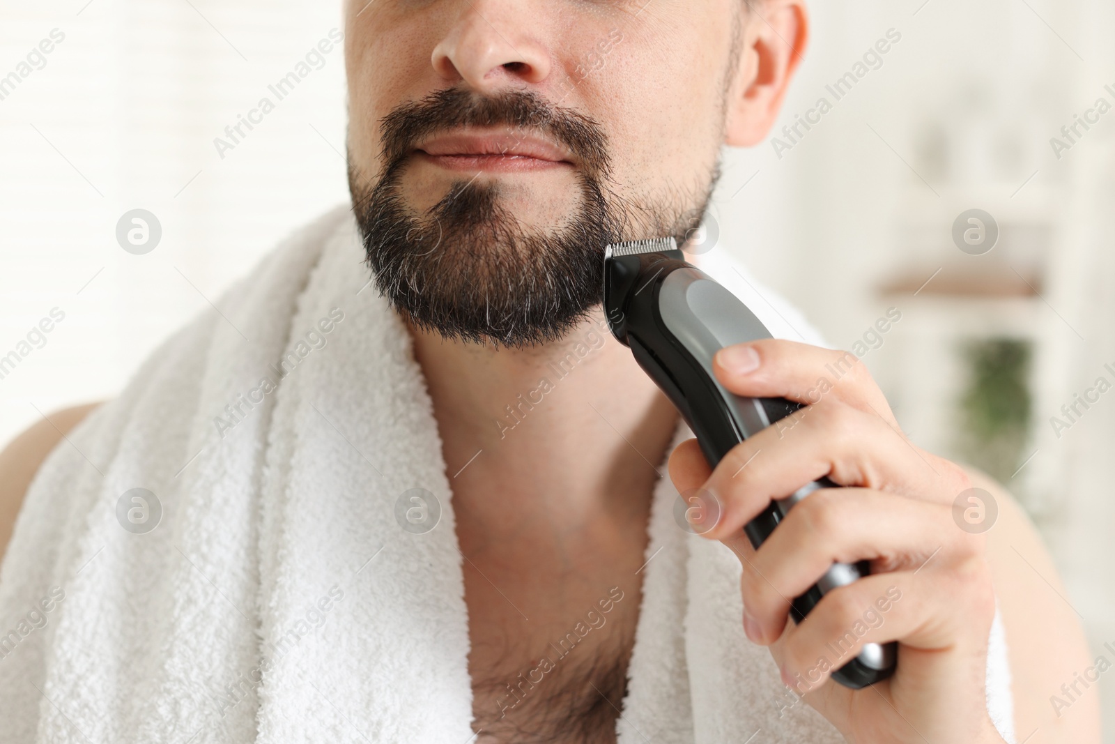 Man shaving with trimmer at home, closeup Photo of Man shaving with trimmer at home, closeup
