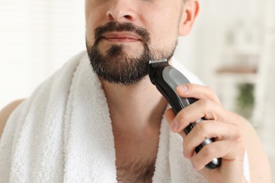 Photo of Man shaving with trimmer at home, closeup