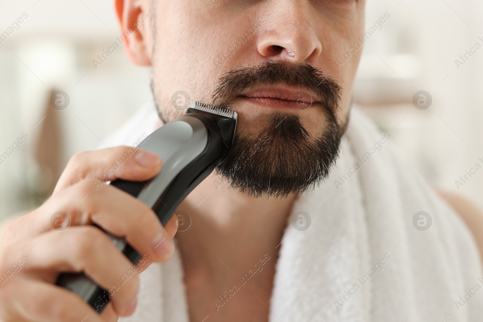 Man shaving with trimmer at home, closeup Photo of Man shaving with trimmer at home, closeup
