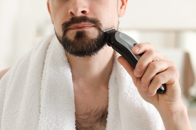 Photo of Man shaving with trimmer at home, closeup