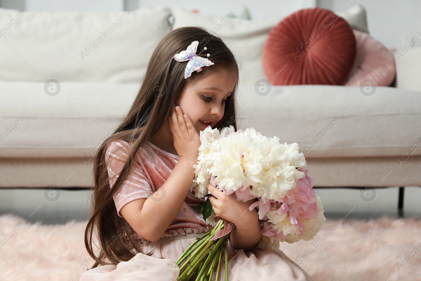Cute little girl with bouquet of beautiful peonies on floor at home Photo of Cute little girl with bouquet of beautiful peonies on floor at home