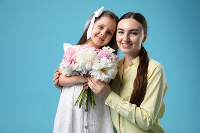 Photo of Mother and her daughter with bouquet of beautiful peonies on light blue background