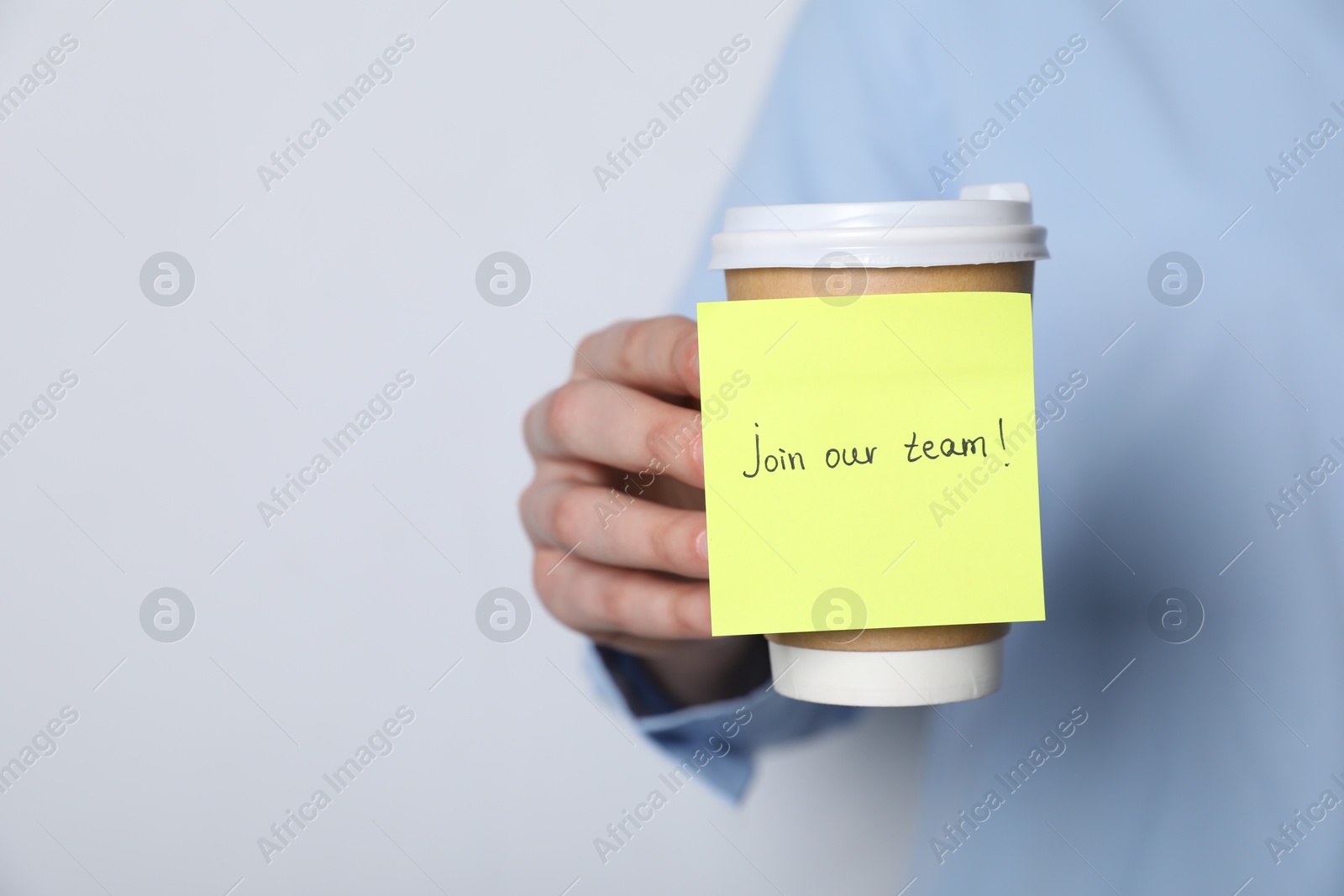 Join Our Team. Woman holding takeaway cup with sticky note on grey background, closeup. Space for text Photo of Join Our Team. Woman holding takeaway cup with sticky note on grey background, closeup. Space for text