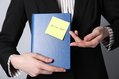 Photo of Join Our Team. Human resources manager holding notepad with sticky note on grey background, closeup