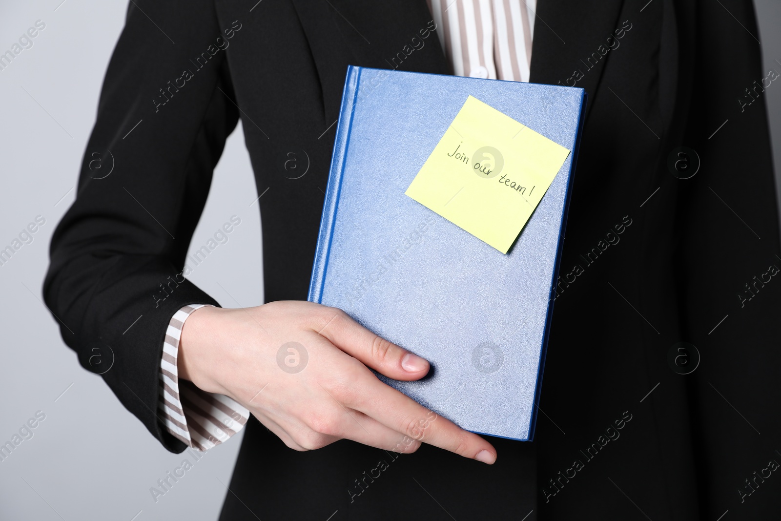 Photo of Join Our Team. Human resources manager holding notepad with sticky note on grey background, closeup