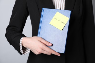 Photo of Join Our Team. Human resources manager holding notepad with sticky note on grey background, closeup