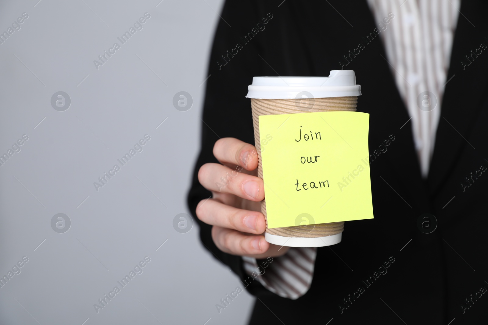 Join Our Team. Human resources manager holding takeaway cup with sticky note on grey background, closeup. Space for text Photo of Join Our Team. Human resources manager holding takeaway cup with sticky note on grey background, closeup. Space for text
