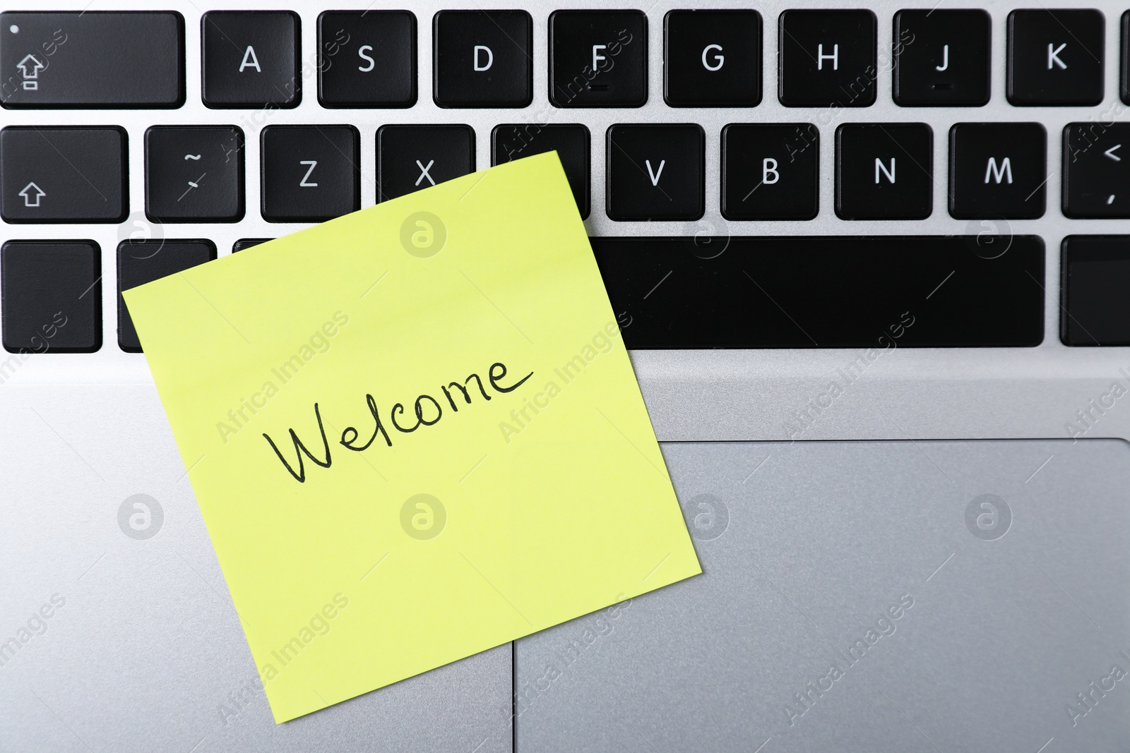 Paper note with word Welcome on laptop, top view Photo of Paper note with word Welcome on laptop, top view