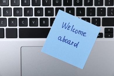 Photo of Paper note with words Welcome Aboard on laptop, top view