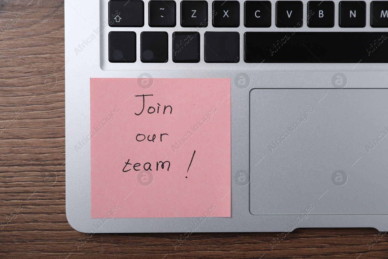 Paper note with words Join Our Team and laptop on wooden table, top view Photo of Paper note with words Join Our Team and laptop on wooden table, top view
