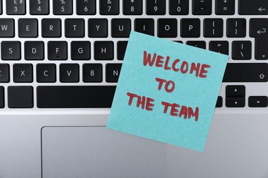 Photo of Paper note with words Welcome To The Team on laptop, top view
