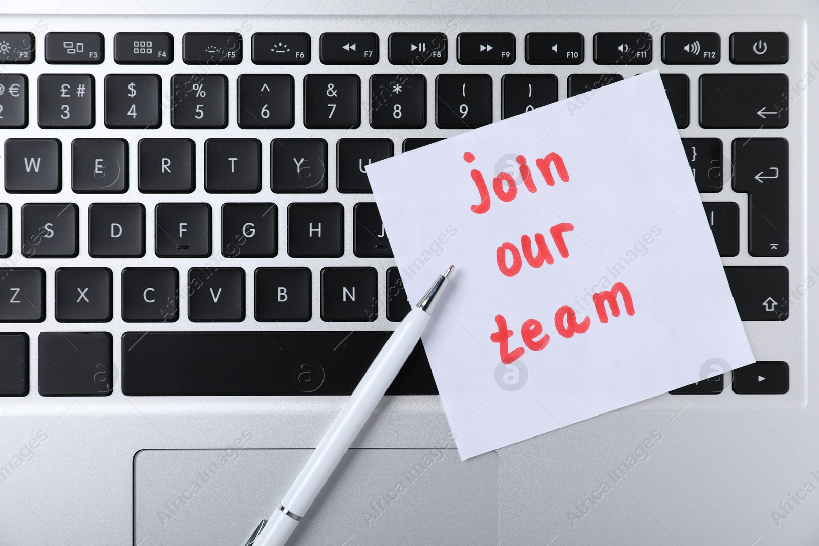 Paper note with words Join Our Team and pen on laptop, top view Photo of Paper note with words Join Our Team and pen on laptop, top view