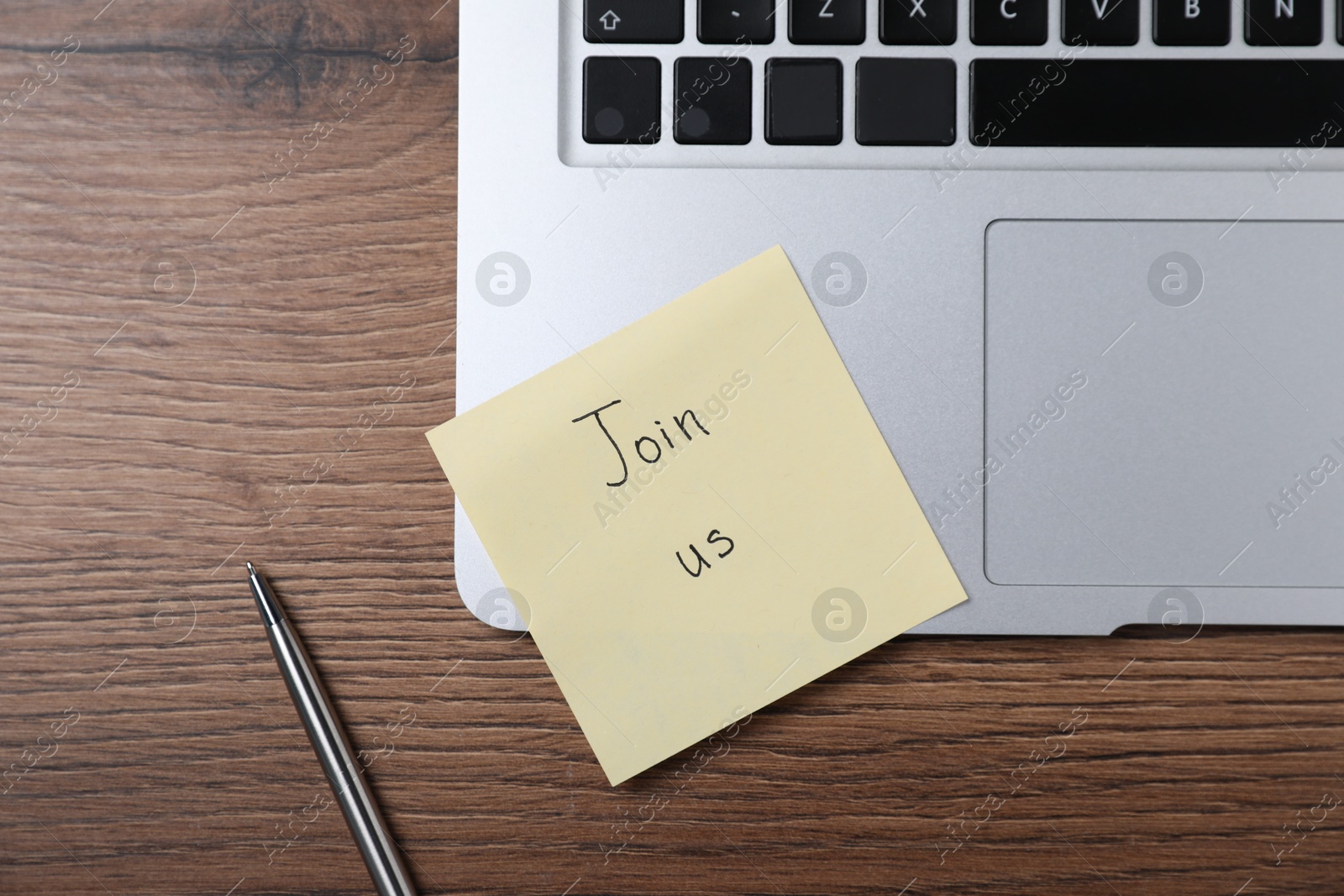 Paper note with words Join Us, laptop and pen on wooden table, flat lay Photo of Paper note with words Join Us, laptop and pen on wooden table, flat lay